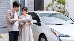 車の前で手続き書類の内容を確認する様子