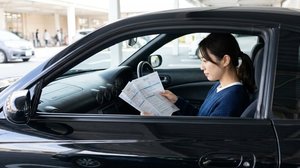 運転席で自動車保険の契約書類を確認する様子