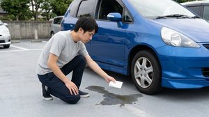 車体下から地面に漏れ出た液体を確認する様子