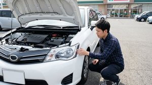 ボンネットを開けて車のヘッドライトを点検する様子