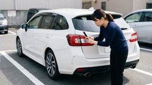車のバンパーの傷をスマホで撮影して記録する様子