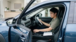 運転席で車両の保証書や点検書類を確認する場面