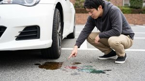 車の下の地面に漏れ出た複数色の液体