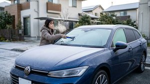 凍結したフロントガラスの霜をスクレーパーで削り落とす作業