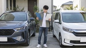 2台の車を前に保険書類を確認
